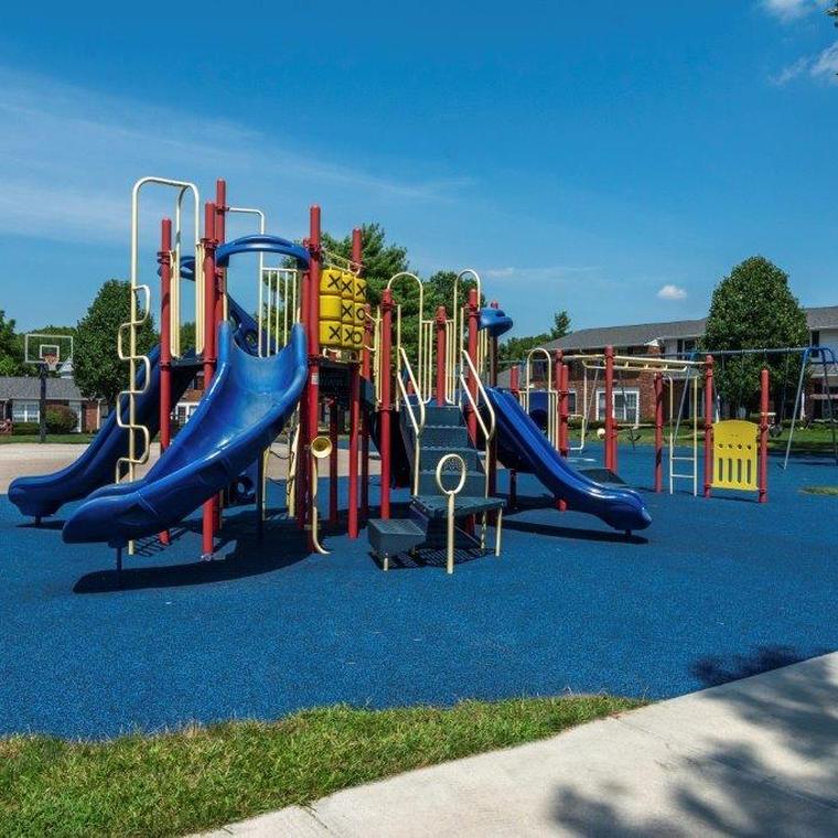 Play gym with plastic slides and metal poles and railing on a blue rubber surface