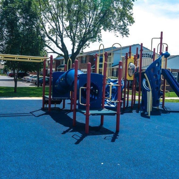 Metal monkey bars and plastic tunnel on blue rubber surface