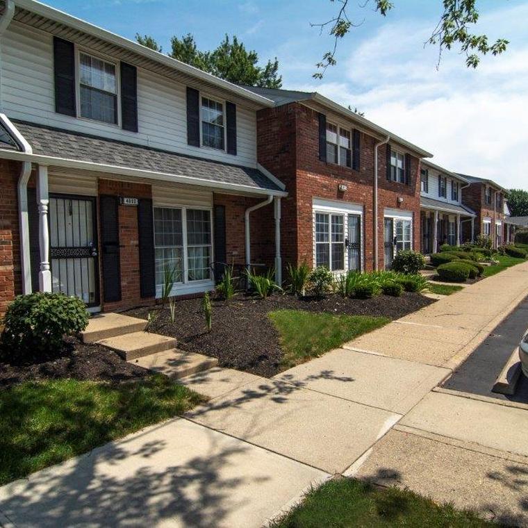 apartment exterior with lush green landscaping and concrete sidewalk